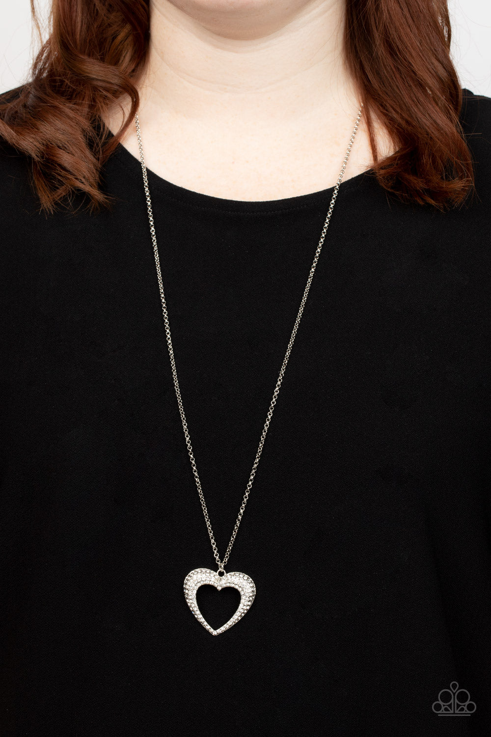 A flared silver heart is encrusted in glassy white rhinestones, resulting in a romantic shimmer at the bottom of an extended silver chain. Features an adjustable clasp closure.  Sold as one individual necklace. Includes one pair of matching earrings.